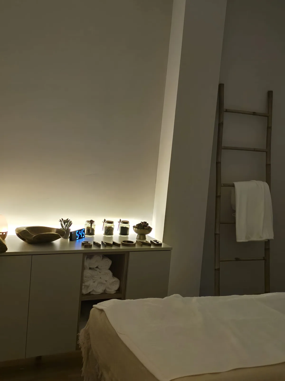 Detalles del espacio de Simone: toallas, productos y luz suave junto a la camilla.